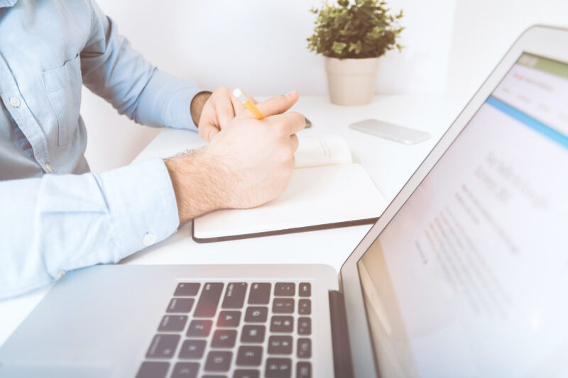 hands on a notebook with an open laptop