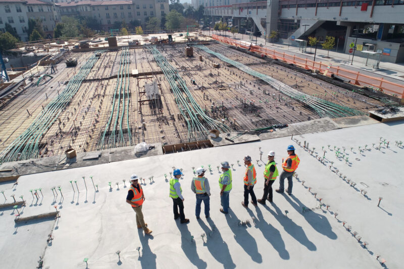 several people wearing orange vests overlooking a construction site