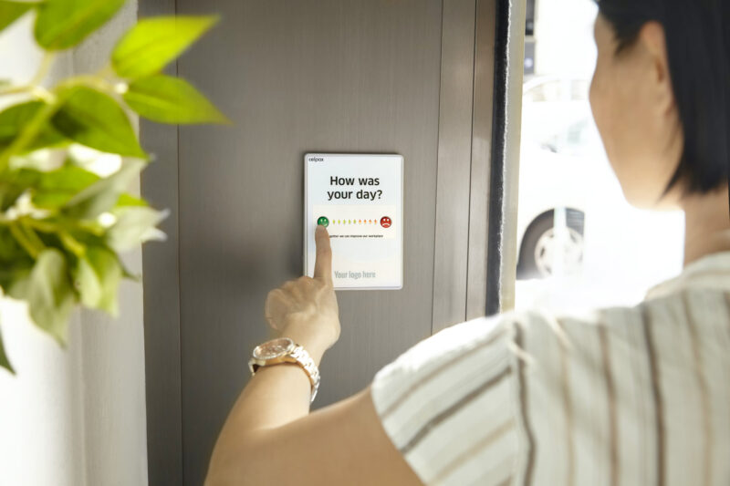 A woman presses a button on a screen with a happy and a mad emoji